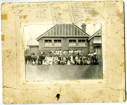 Charlton State School c. 1909. Students and teacher standing in front of school brick building. Teacher: Eric Stubbs. 129 students from prep to seniors. 4 adults. 