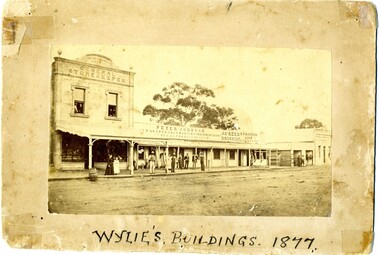 Peter Johnson's bridge store, High Street Charlton. Titled Wylie's Building 1877. Group of people on footpath.