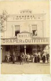 W. Wylie Store,  c.1890s. Nine people standing out front (store workers ), three others in the second story window, two of these are children. One person on a bicycle out front.