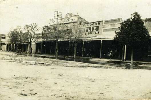 1911 Flooded High Street, showing street store front, Wylies general store in the middle withe Goldern Fleece Hotel.