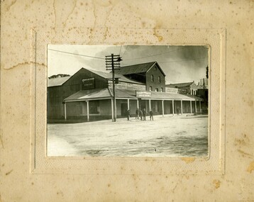Five men in front of service Station, one man in front of Massey Harris building. 