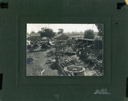 Foundry backyard showing farm machinery and implements. Three workmen in the yard. 