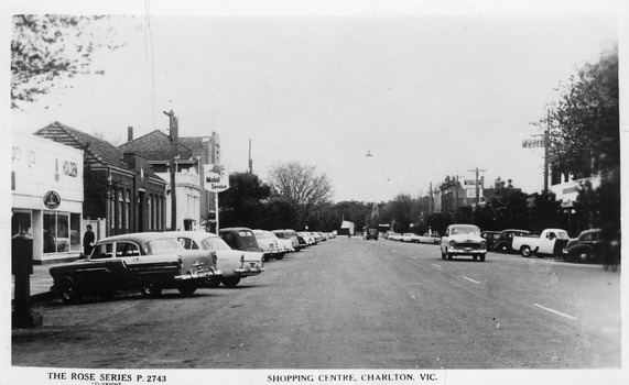 Looking down main street of Charlton, cars and store fronts either side. Holden garage and postoffice on left. Pub on right.