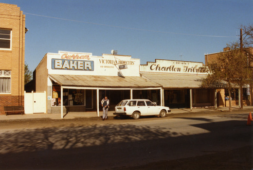  Curran's Bakery, Victorian Producer's Co-operative and the Charlton Tribune Office. White Car parked in fron of VPC office. Man crossing the street toward photographer. 