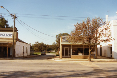 Butchers building looking at side street, formely William Street. One person walking in front of shop. Real Estate agent on the other corner.
