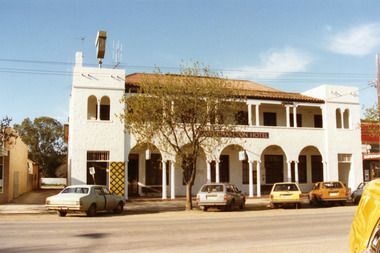 East Charlton Hotel, mexican style white two storey buliding, arches and pillars in front. Car parked in street in front of building.