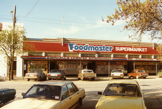Single storey Foodmaster SUPERMARKET building. Red, white and blue signage on the verandah reads O'DONNELL'S LICENCED SUPERMARKET, and WOOL Haberdashery.