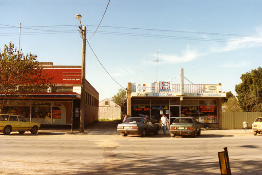 single storey building. Signage on the windows reads Lou's CAFE and on the awning Lou's MILK Bar. Fresh Fruit VEGS, meals, TAKE AWAY FOOD, FISH & CHIPS, HAMBURGERS. 