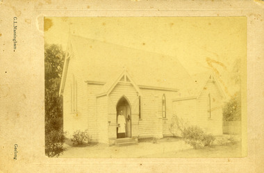 A cleric stands in the doorway to the weatherboard church.