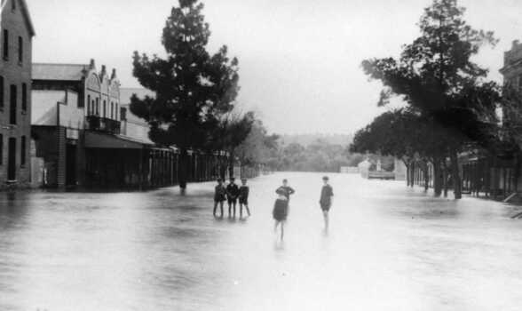 1909 flood. Children standing in floodwater in High Street. Looking west from corner of Armstrong Street, Charlton.