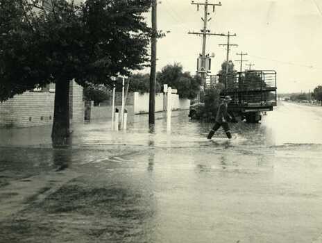 1972 Flash flood. Cnr High Street and Armstrong Street Charlton. Man crossing road through flood water, Truck behind.