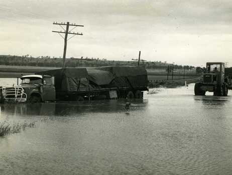 Road transport run off Calder Highway in flood water. Shire grader trying to remove truck.