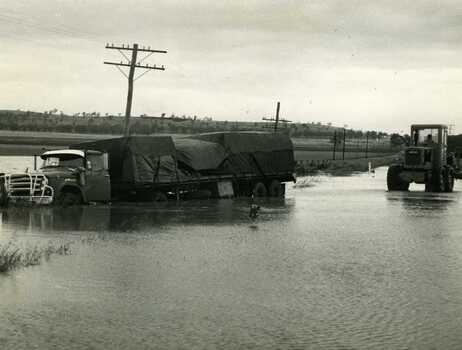 Road transport run off Calder Highway in flood water. Shire grader trying to remove truck.