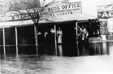 Flood, with people standing in front of Charlton Tribune Office. 10 people, 4 are wearing work aprons.