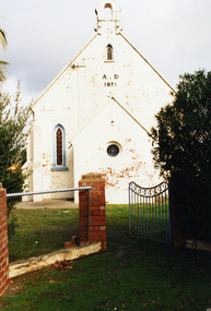 Front view of white painted Church. Looking through the front gate. Lettering on church reads A.D. 1871