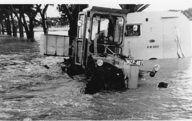 CRB grader towing a caravan through flood water.