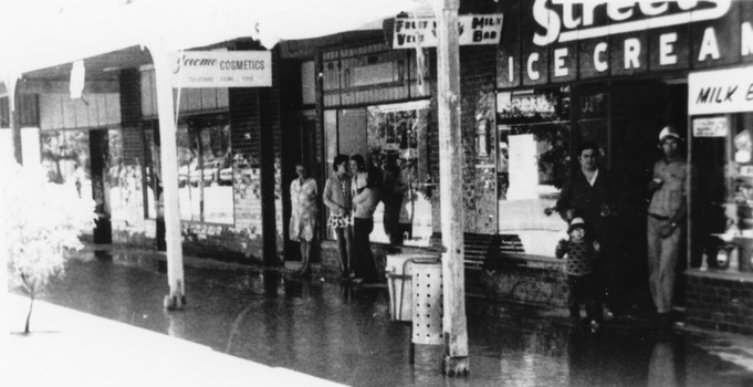 Flooded High St, Charlton. Shopkeepers standing in front of their stores.
