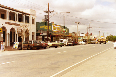 Pub and shops on High Street, various cars are parked in front.