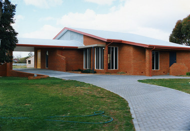 Entrance to Red brick church with driveway leading up to door.