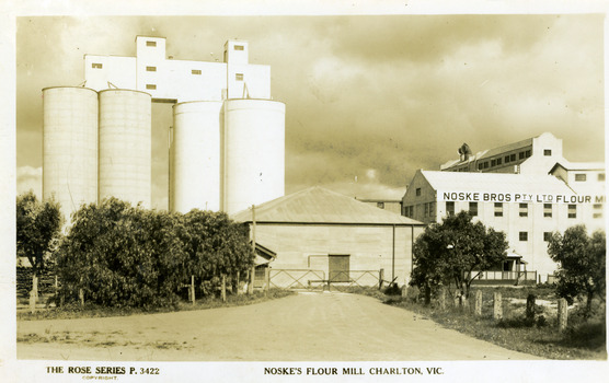 Four tall concrete silos stand next to brick flour mill.