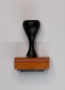 Rubber stamp with black handle and rose coloured base.