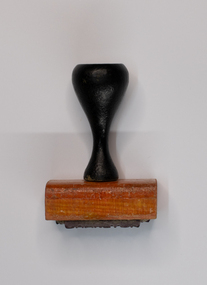 Rubber stamp with black handle and rose coloured base.
