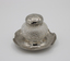 Glass inkwell with silver lid, standing on silver dish stand.