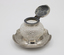 Glass inkwell with open silver lid, standing on silver dish stand.