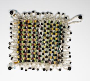 Handmade Table Mat of small glass beads  in plain weave. Colours used are black, green and yellow.