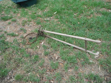 Scarifier hand hoe with wooden handles and a metal wheel.