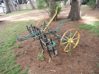 Twelve blade green 5-6 horse scarifier with  surface rust with two large yellow wheels and brake.