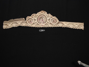 Piece of lace with circular motifs on edge and three larger circles in middle embroidered with colour.