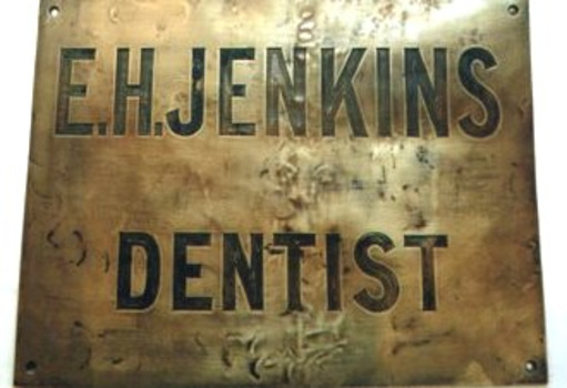 Brass plate with 'E.H. JENKINS DENTIST' engraved on surface