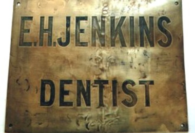 Brass plate with 'E.H. JENKINS DENTIST' engraved on surface