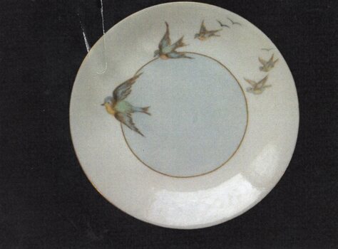 Bread and butter plate with gold border at rim and gold inner circle.  5 swallows and 3 stylised birds hand-painted by Margaret Amess.