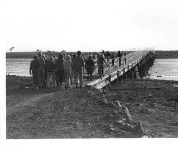 Photograph of People Walking Across a Bridge