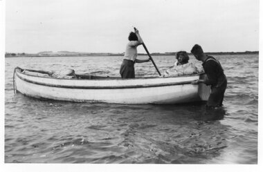Photograph of three people and a boat, c.1940s