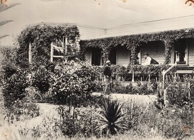 Photograph of two men talking on the balcony of Amess House