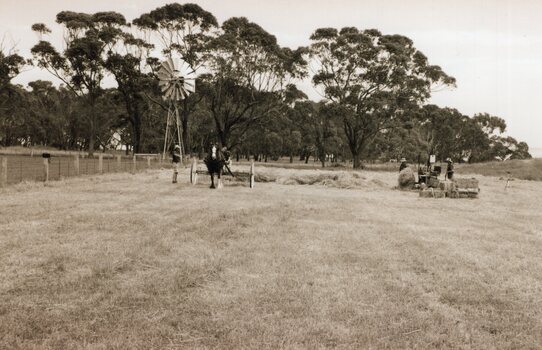 Photograph of people gathering hay