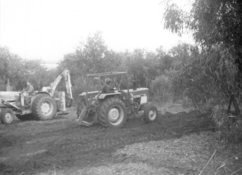 Photograph of two people operating farm machinery