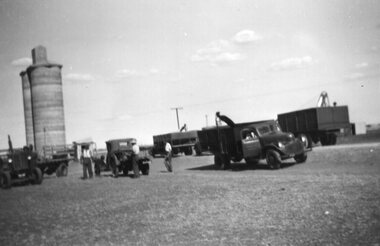 Photograph of line of trucks and silo