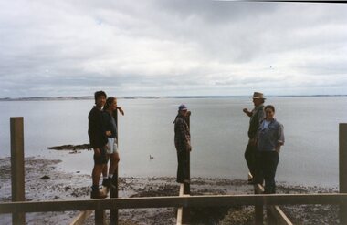 Photograph of people balancing on horizontal struts of jetty.