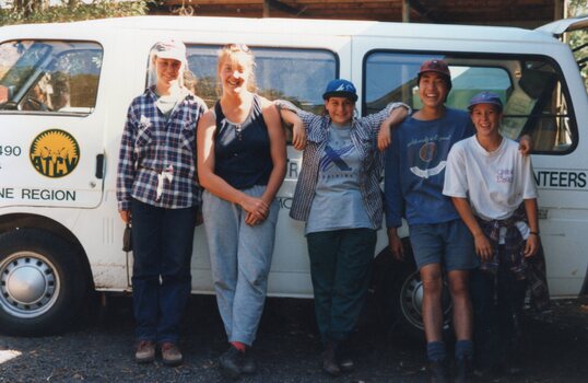 Photograph of people standing in front of a minibus