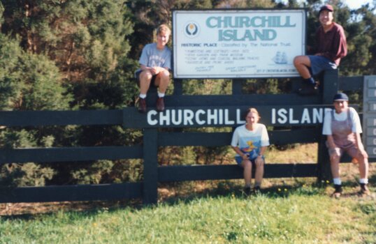 Photograph of people posing around a sign