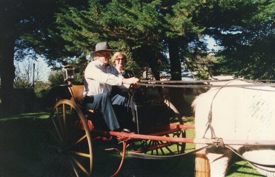 Photograph of two people riding in a buggy