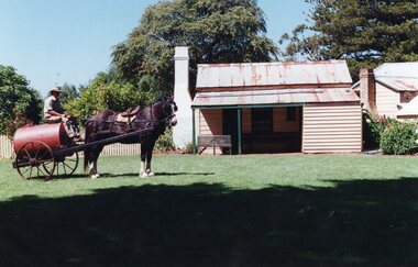 Photograph of a horse and barrel standing outside Rogers Cottage