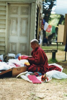 Photograph of Tibetan monk folding clothes into a trunk