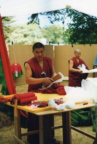 Photograph of a Tibetan monk unwrapping items