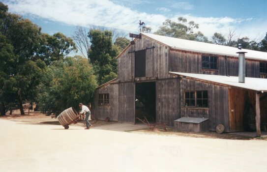 Photograph of a wooden barn and man