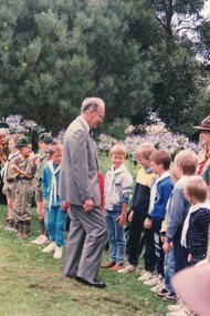 Photograph of man greeting a line of children